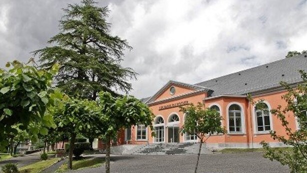 A building with a red facade, arched windows, and a sign that reads "Hotel". - T2 Apartment Cauterets Center - 4 People, Wifi (Cauterets)