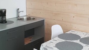 A kitchen with a coffee maker, sink, and a clock on the wall. - T2 Apartment Cauterets Center - 4 People, Wifi (Cauterets)