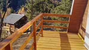 A wooden deck with a railing overlooking a mountainous landscape.