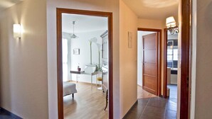 A hallway with a wooden door, a small table with a chair, and a lamp.