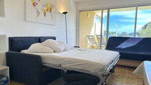 A modern bedroom with a bed, bedside tables, a lamp, and a view of the outdoors.