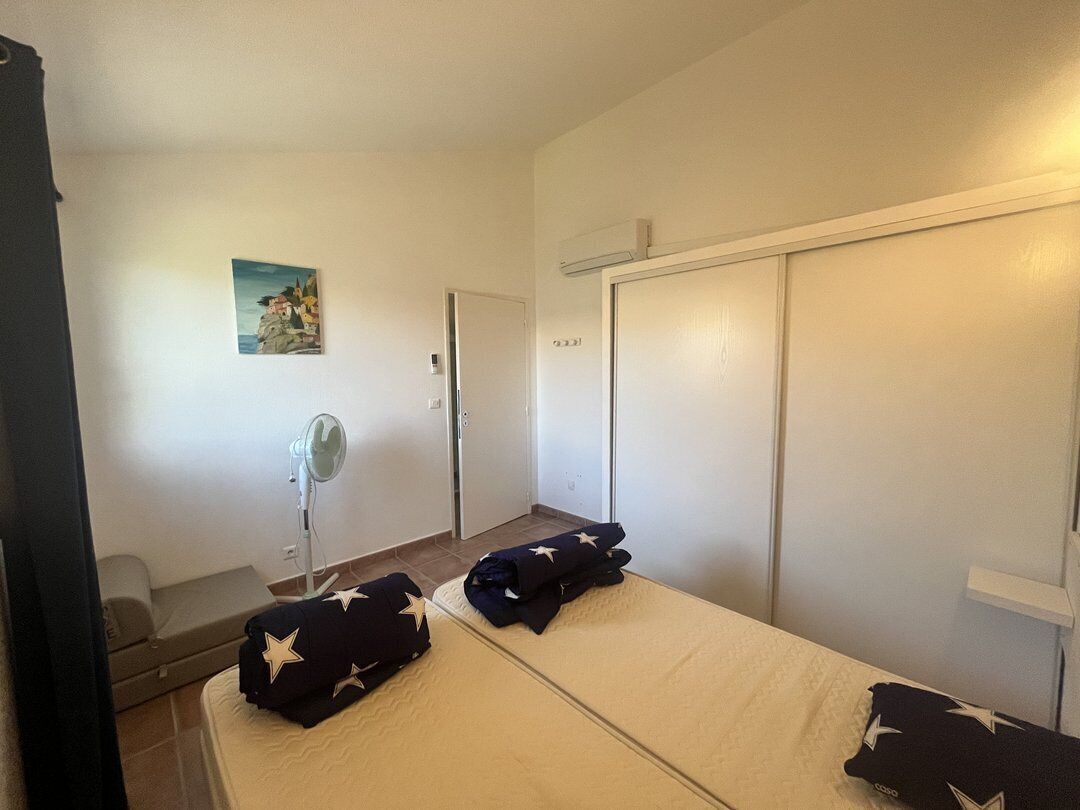 A room with two beds, a fan, a painting, and a wardrobe.