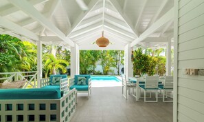 A covered outdoor area with white furniture, a pool, and lush greenery. - Karibuni Villa / Private Pool and Jacuzzi / 200M from Las Ballenas Beach / WIFI (Las Terrenas)