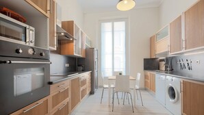 Una cucina moderna con forno a incasso, microonde e lavatrice. C'è un'area pranzo con tavolo e sedie.