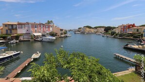 Un port de plaisance où sont amarrés des bateaux, entouré de bâtiments aux couleurs vives et de verdure.