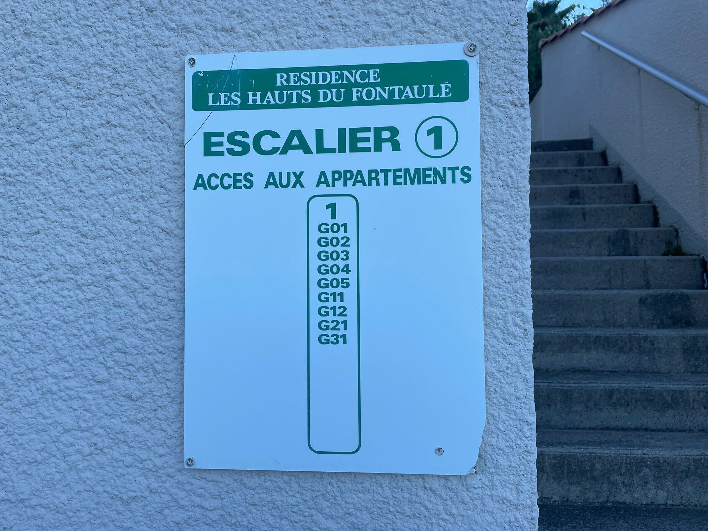 Placa indicando uma escada que dá acesso a apartamentos com as etiquetas G01 a G31.