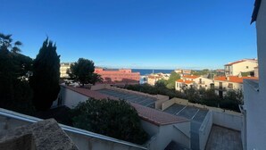 A residential area with buildings, a clear sky, and a distant view of the sea.