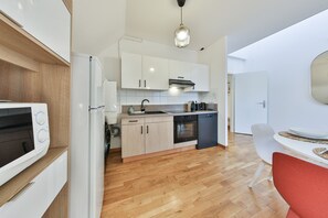 Una cocina moderna con armarios blancos, horno empotrado y lavavajillas.