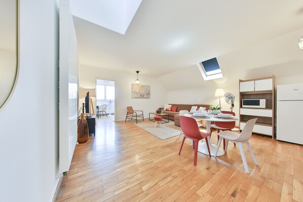 Amplia sala de estar con mesa de comedor, sillas, sofá y área de cocina con microondas y armarios.