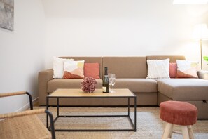 Una sala de estar con un sofá beige, dos sillones, una mesita de centro y un pequeño reposapiés.
