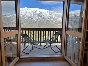 En balkong med två stolar och utsikt över snötäckta berg.
