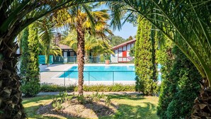 Ein Swimmingpool, umgeben von üppiger Vegetation und einem Gebäude mit rotem Dach.