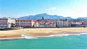 Eine Küstenstadt mit bunten Gebäuden, einem Strand und Bergen im Hintergrund.