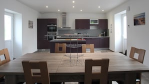 Una cocina moderna con armarios oscuros, una isla central y una zona de comedor con sillas de madera.