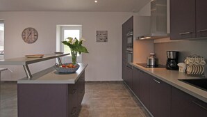 Una cocina moderna con gabinetes oscuros, una isla central y una cafetera.