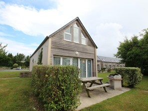 A two-story building with a pitched roof, large windows, and a picnic table in the foreground. - Detached house near dunes in La Hague, pets allowed, parking (La Hague)