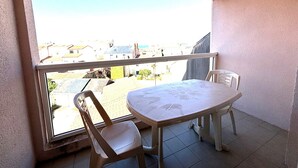 A balcony with a table and two chairs, overlooking a residential area. - 2-Bedroom Apartment - 50m from the beach, parking (Les Sables-d'Olonne)