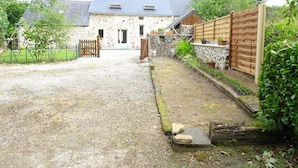 Een stenen huis met een grindpad dat leidt naar een houten poort.