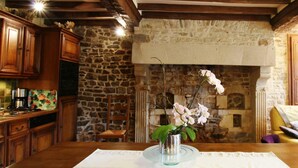 A rustic kitchen with wooden cabinets, a stone wall, and a fireplace. - Comfortable house in the heart of the Norman bocage with garden and pets allowed (Doville)