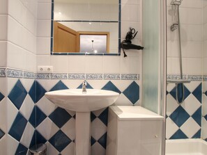 A bathroom with a white sink, a mirror, and a shower area.