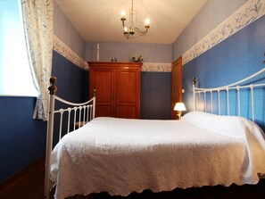 A bedroom with a white bed, wooden wardrobe, and a chandelier.