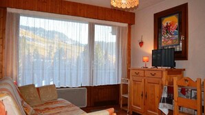 A cozy room with a wooden sofa, a television, and a painting on the wall.