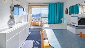 A modern hotel room with a kitchenette, a dining area, and a large window offering a city view. - Charming downtown studio with pool near Grande Plage (Biarritz)