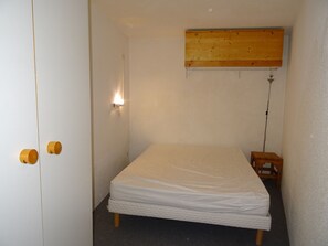 Cozy retreat with a single bed, wooden headboard, and a small stool.