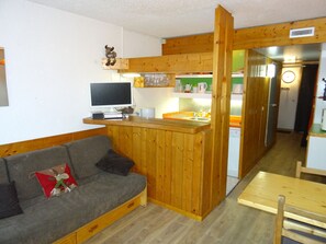 Cozy living space with a kitchenette, sofa, and TV.