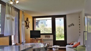 Una sala de estar acogedora con un sofá, un televisor y un comedor con una mesa y sillas.