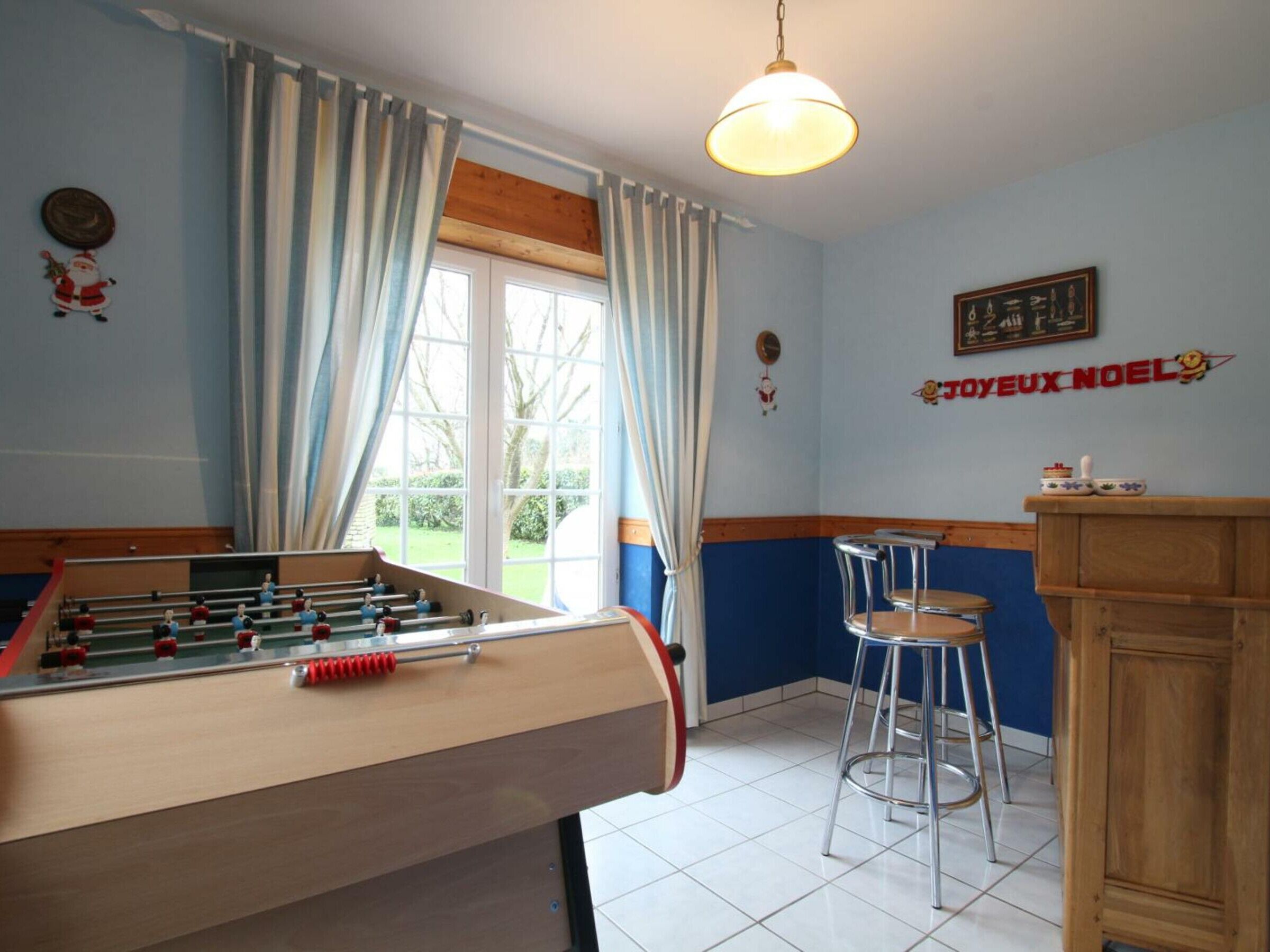 Une pièce avec une table de baby-foot, un tabouret de bar et une fenêtre avec des rideaux.