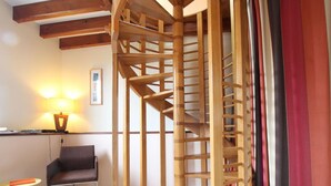 A room with a wooden spiral staircase, a chair, a small table, and a lamp. - Charming cottage with Internet near Mont Saint-Michel (Les Chambres-Le Grippon)