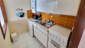 A compact kitchen with white cabinets, a built-in oven, and a coffee maker.