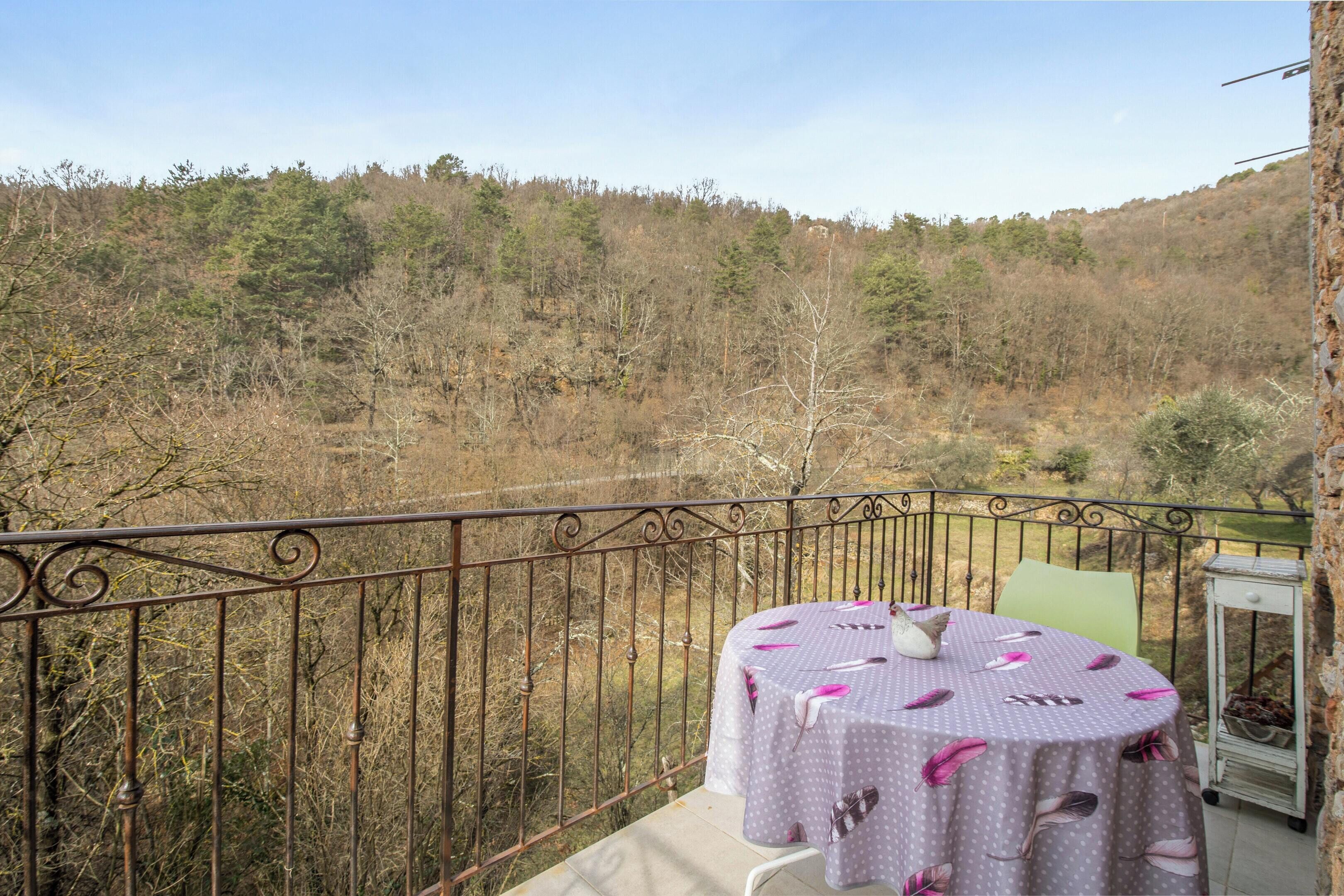 Ein Balkon mit Tisch für zwei Personen mit Blick auf einen bewaldeten Hang.