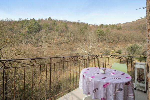 Un balcón con una mesa lista para dos personas, con vistas a un paisaje boscoso.