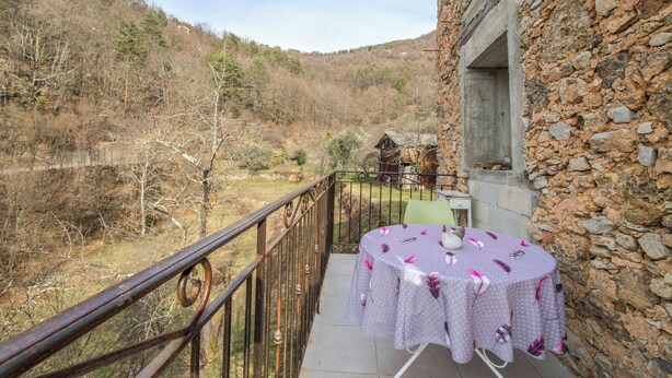 Un balcon avec une table dressée pour deux personnes, offrant une vue sur un paysage montagneux.