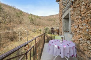 Un balcon avec une table dressée pour deux personnes, offrant une vue sur un paysage montagneux.