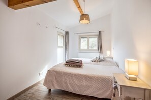 A bedroom with a bed, bedside table, lamp, window, and ceiling light.