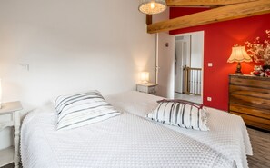 Ein Schlafzimmer mit zwei Betten, einem Schminktisch, einer Lampe und einer roten Akzentwand.
