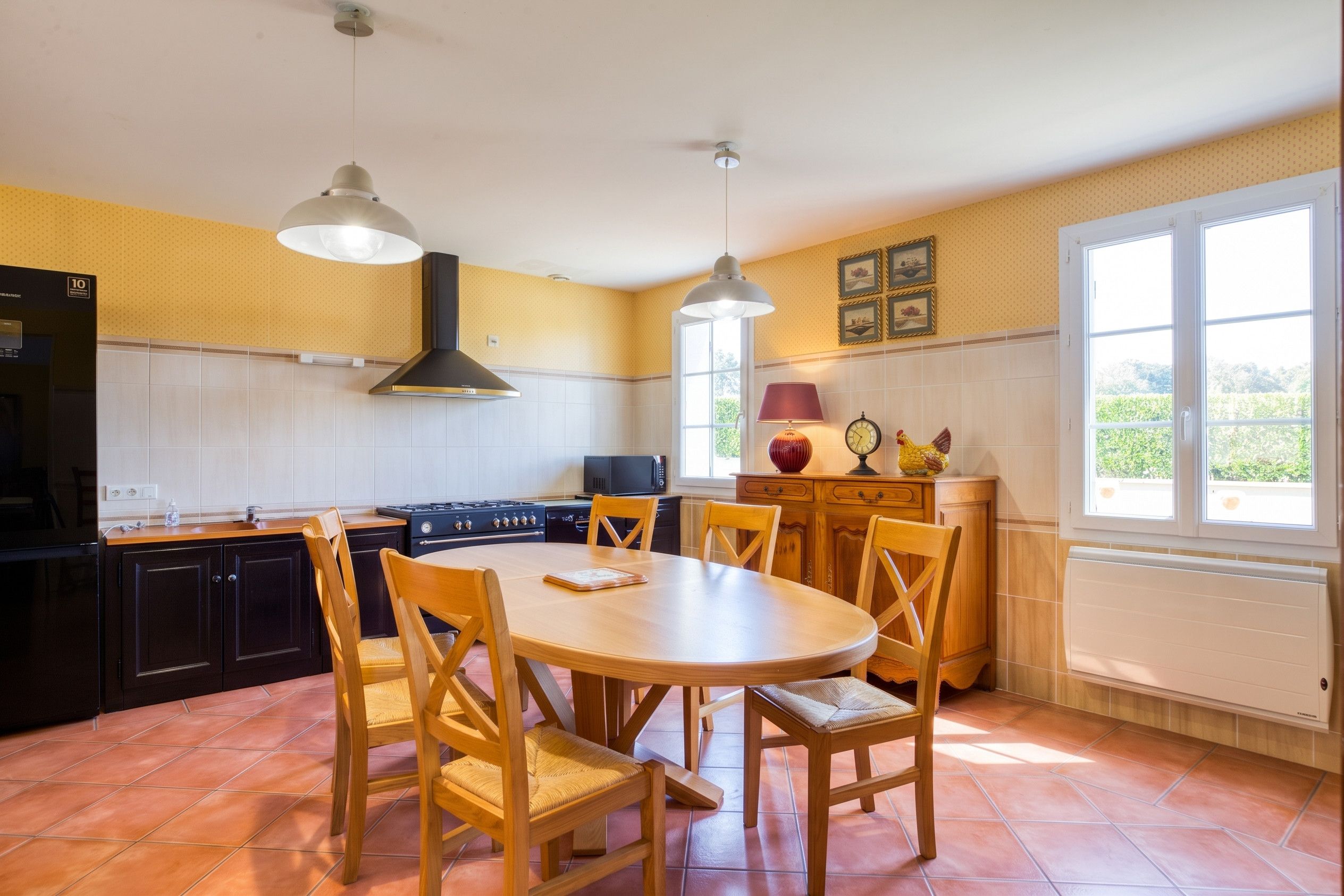 A kitchen with a round wooden table, chairs, a stove, and a microwave.