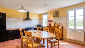A kitchen with a round wooden table, chairs, a stove, and a microwave.