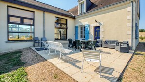 A patio area with outdoor furniture, a dining table, and a blue door.