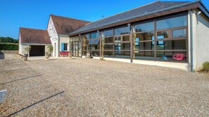 A building with large windows, a gravel driveway, and a red bench.