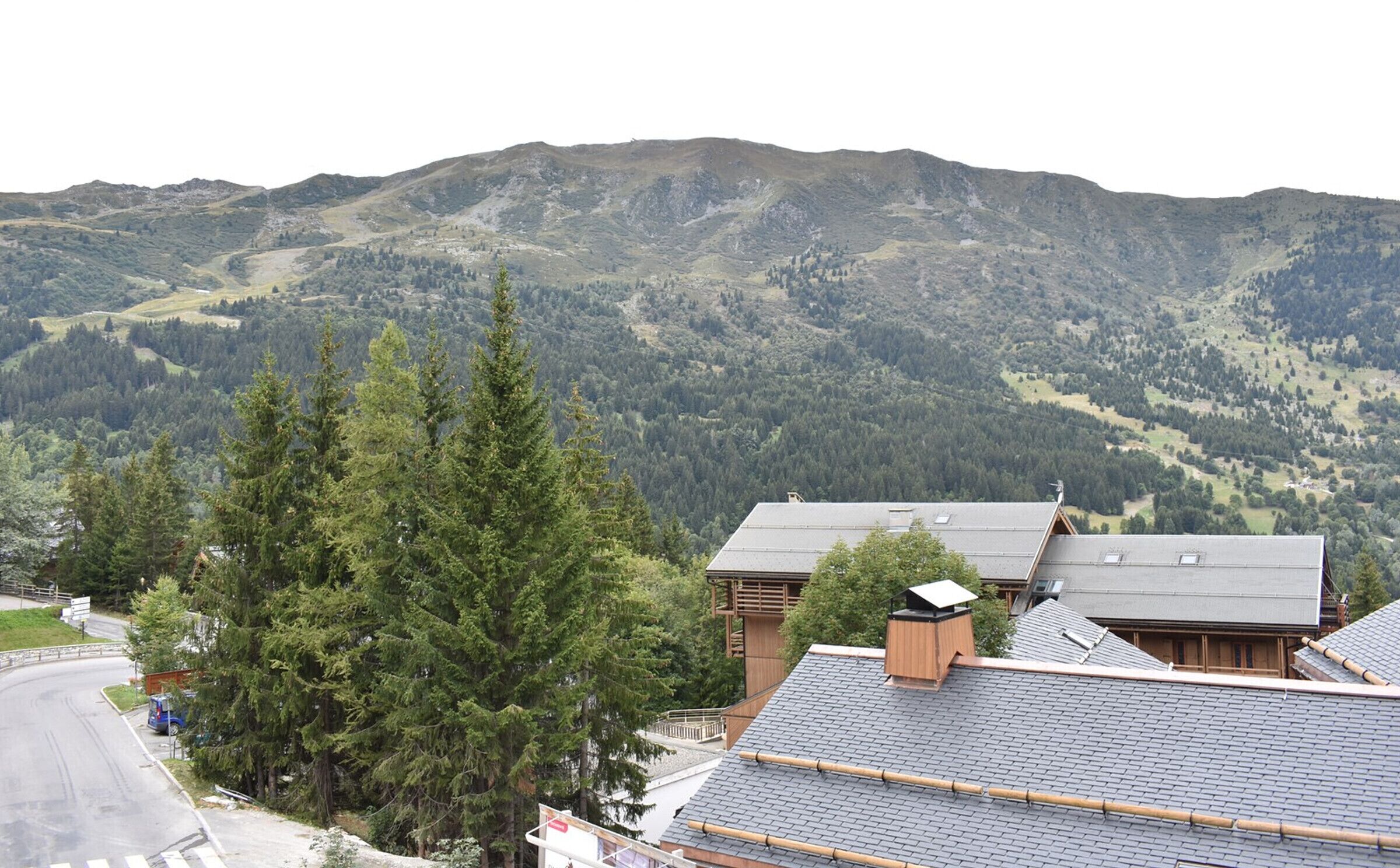 Un paysage de montagne avec une zone résidentielle comprenant des maisons traditionnelles en bois, dotées de toits inclinés.