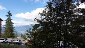 A parking area with cars, a pedestrian, and a mountain view in the background. - Cozy studio with mezzanine for 4 people in Arc 1800, near slopes and WiFi included (Les Arcs 1800)