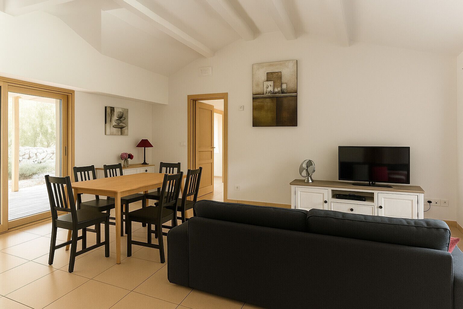 A living room with a sofa, a TV, a dining table with chairs, and a painting on the wall.