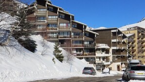 A multi-story hotel with balconies, a ski slope in the background, and snow-covered surroundings. - Cozy studio for 2 near slopes with balcony and parking – Auris en Oisans (Auris)