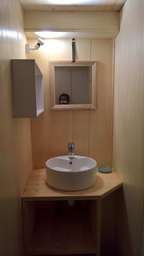 A small bathroom with a wooden vanity, a sink, and a mirror. - Logement insolite super confort, piscine chauffée (Entrepierres)