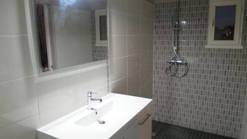 A bathroom with a white sink, a mirror, and a shower.