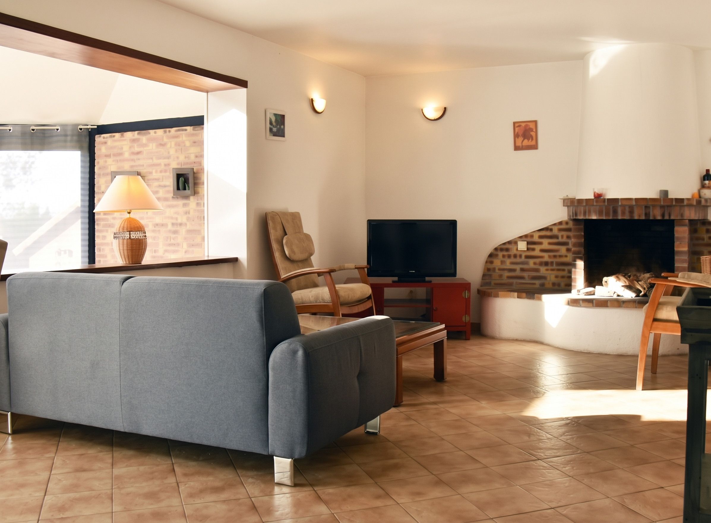 Een woonkamer met een bank, een televisie, een open haard en een raam met uitzicht.